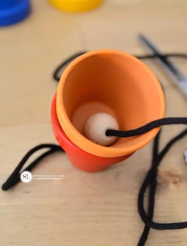 Thread the flower pots through the other side of the knotted string, and add another wooden bead - make sure the bead is larger than the small hole at the bottom of the flower pot
